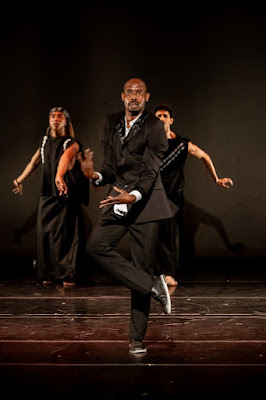 Performers dancing on a stage in a theatrical performance setting.