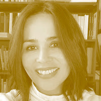 Cláudia Lucas Chéu: Retrato de uma mulher sorrindo em tom sépia, com uma estante de livros ao fundo.