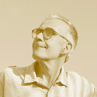 António Lobo Antunes: Retrato em tons de sépia de um homem idoso usando óculos e camisa polo listrada, olhando para cima e para o lado.