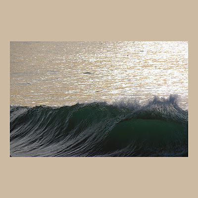 unknown: Uma fotografia de uma onda quebrando no mar com o reflexo do sol na água ao fundo.
