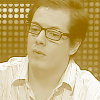 Fábio Porchat: Retrato em tom sépia de um homem usando óculos e camisa listrada.