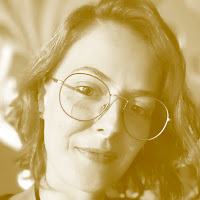 Retrato de uma mulher com óculos redondos em um tom sépia/amarelado.