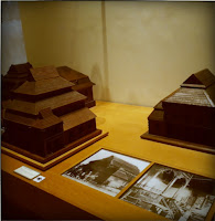 Maquetes de madeira de arquitetura tradicional japonesa em exibição em um museu, com fotografias históricas ao lado.