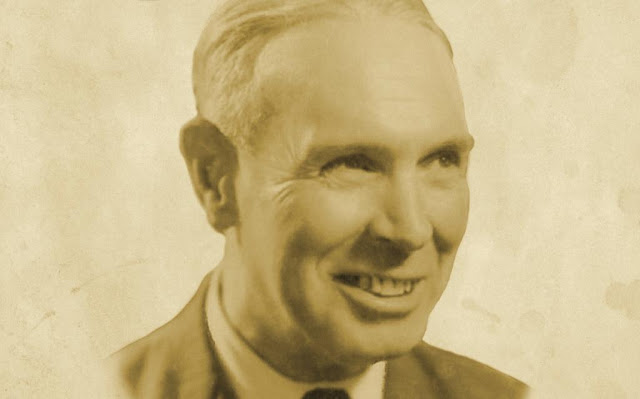 Retrato em tom sépia de um homem sorridente vestindo paletó e gravata.