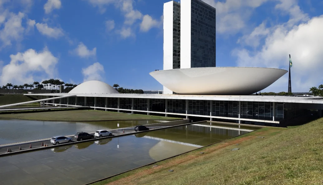 Vista externa do Palácio do Congresso Nacional em Brasília, projetado por Oscar Niemeyer, sob um céu azul com nuvens.