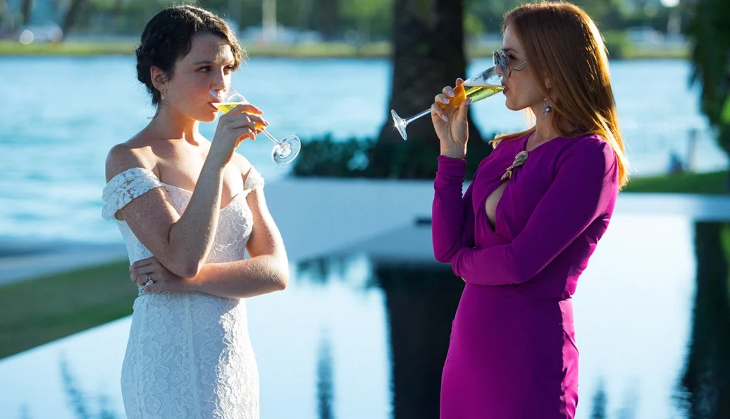Stefania LaVie Owen, Isla Fisher: Uma cena do filme The Beach Bum mostrando duas mulheres bebendo champanhe ao ar livre.