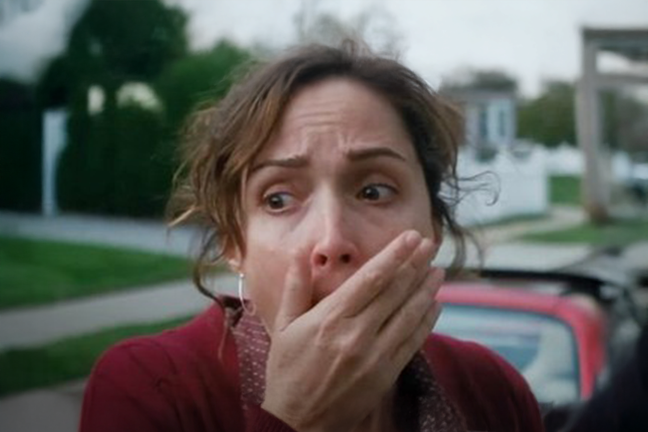 Rose Byrne: Mulher com expressão de choque e horror com a mão sobre a boca, cena do filme Sobrenatural (Insidious).