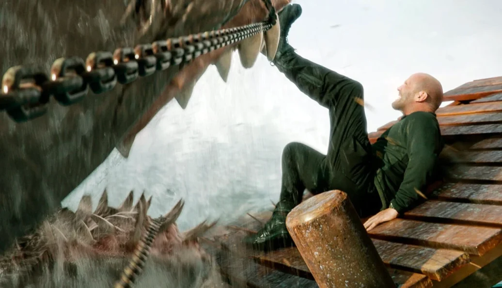 Jason Statham: Cena do filme Megatubarão 2, mostrando um homem chutando o focinho de um tubarão gigante.