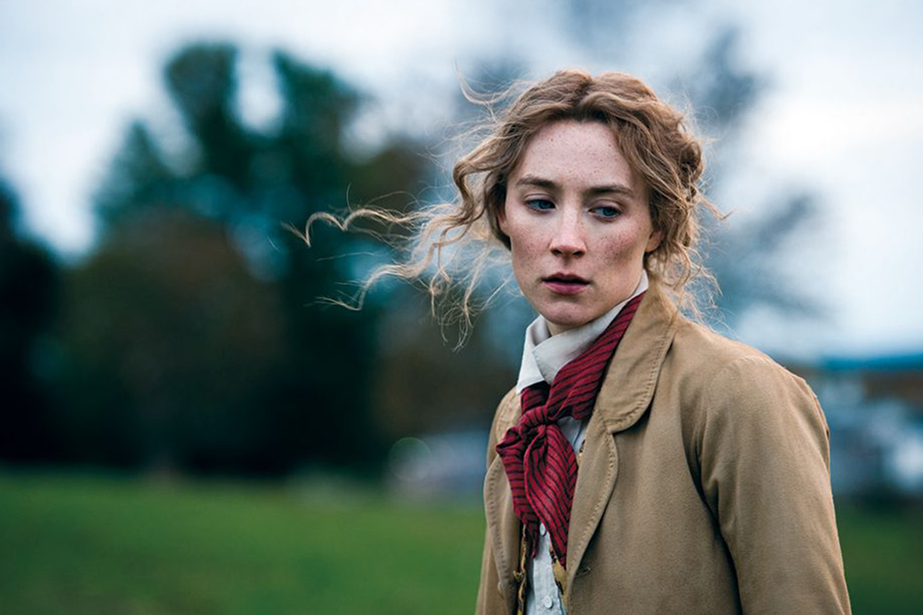 Saoirse Ronan: Uma fotografia de cena do filme Adoráveis Mulheres (Little Women), mostrando a personagem Jo March ao ar livre.