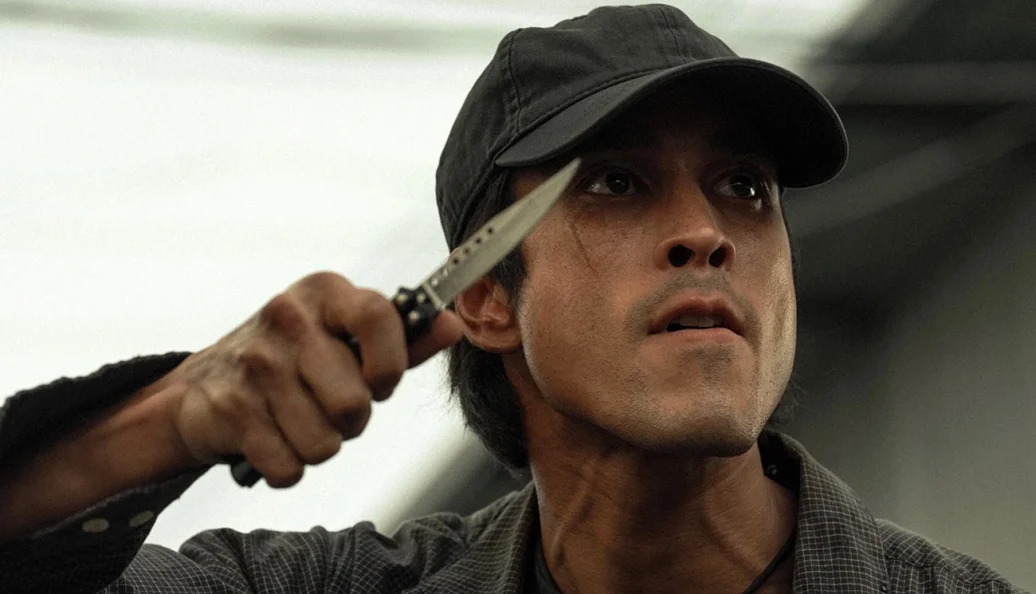 Tony Dalton (Lalo Salamanca): Retrato de um homem com chapéu segurando um canivete borboleta próximo ao rosto.