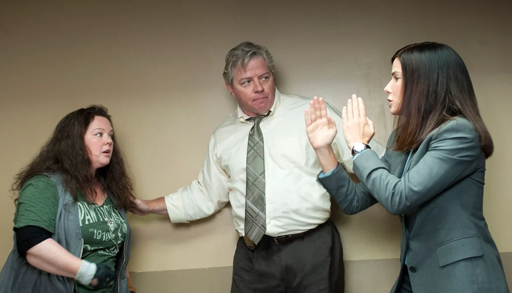 Melissa McCarthy, Thomas F. Wilson, Sandra Bullock: Cena do filme 'As Bem-Armadas' (The Heat) mostrando Sandra Bullock e Melissa McCarthy em uma discussão com um colega.