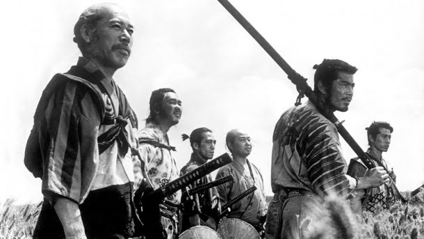 Takashi Shimura, Toshiro Mifune: Fotografia em preto e branco do filme Os Sete Samurais (1954) mostrando um grupo de samurais em um campo.