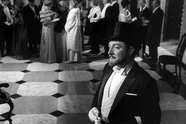 Giorgio Albertazzi: Cena em preto e branco do filme 'L'Année dernière à Marienbad' mostrando um homem de smoking e cartola em um salão luxuoso.