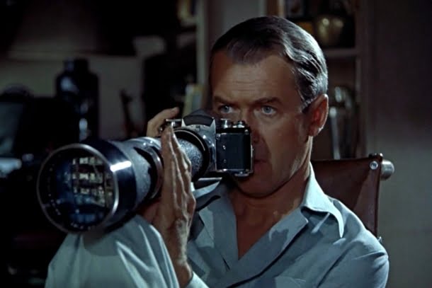 James Stewart: Homem olhando através de uma câmera fotográfica com lente teleobjetiva, cena do filme Janela Indiscreta (Rear Window).