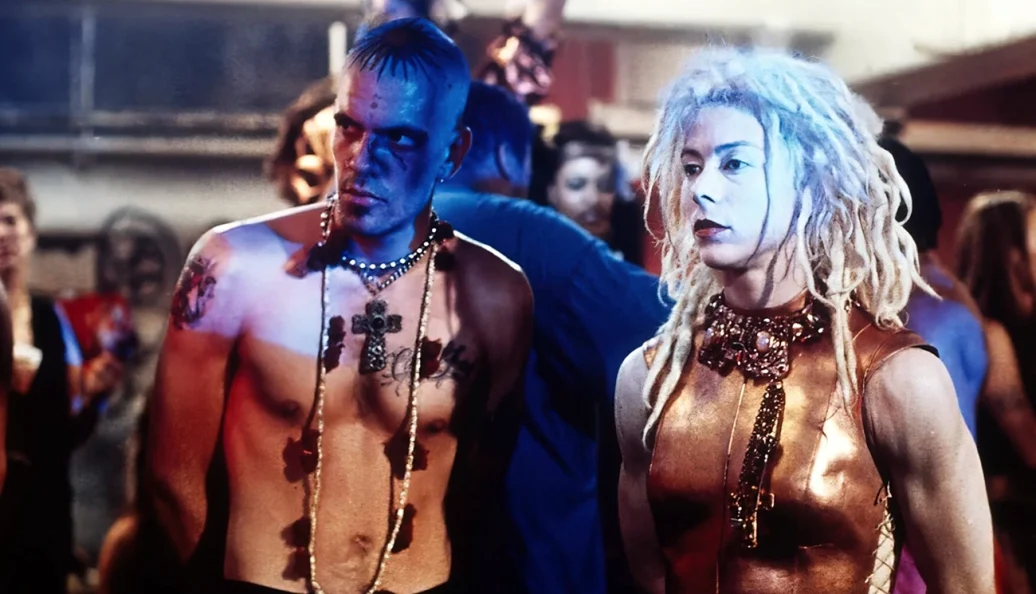 Joe Pantoliano, Belinda McClory: Cena do filme Matrix (1999) mostrando os personagens Cypher e Switch em um ambiente de clube noturno.