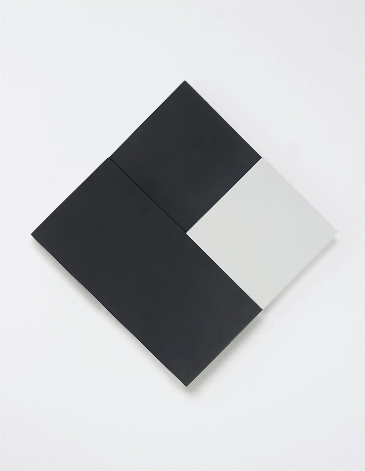 Uma fotografia de uma obra de arte minimalista composta por formas geométricas pretas e brancas dispostas em um losango sobre um fundo branco.