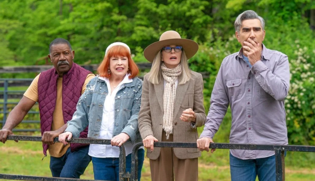 Dennis Haysbert, Catherine O'Hara, Diane Keaton, Eugene Levy: Quatro pessoas com expressões de surpresa e choque paradas atrás de uma cerca de metal em um ambiente rural.