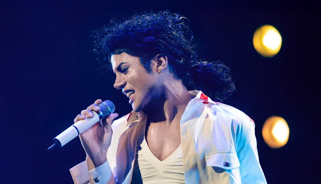Jaafar Jackson: O ator Jaafar Jackson caracterizado como Michael Jackson para a cinebiografia 'Michael', segurando um microfone e cantando no palco.