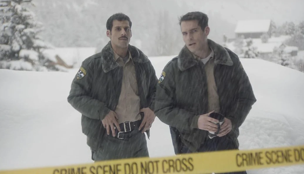 Jim Cummings, PJ McCabe: Still do filme 'The Wolf of Snow Hollow' mostrando dois policiais em uma cena de crime na neve atrás de uma fita de isolamento.