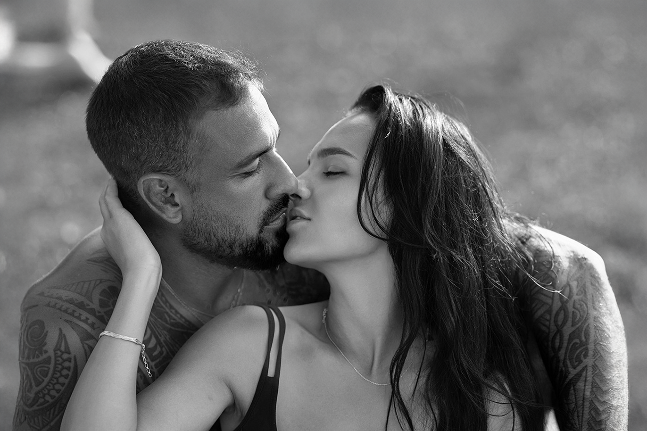 Fotografia artística em preto e branco de um casal em um momento íntimo, prestes a se beijar.