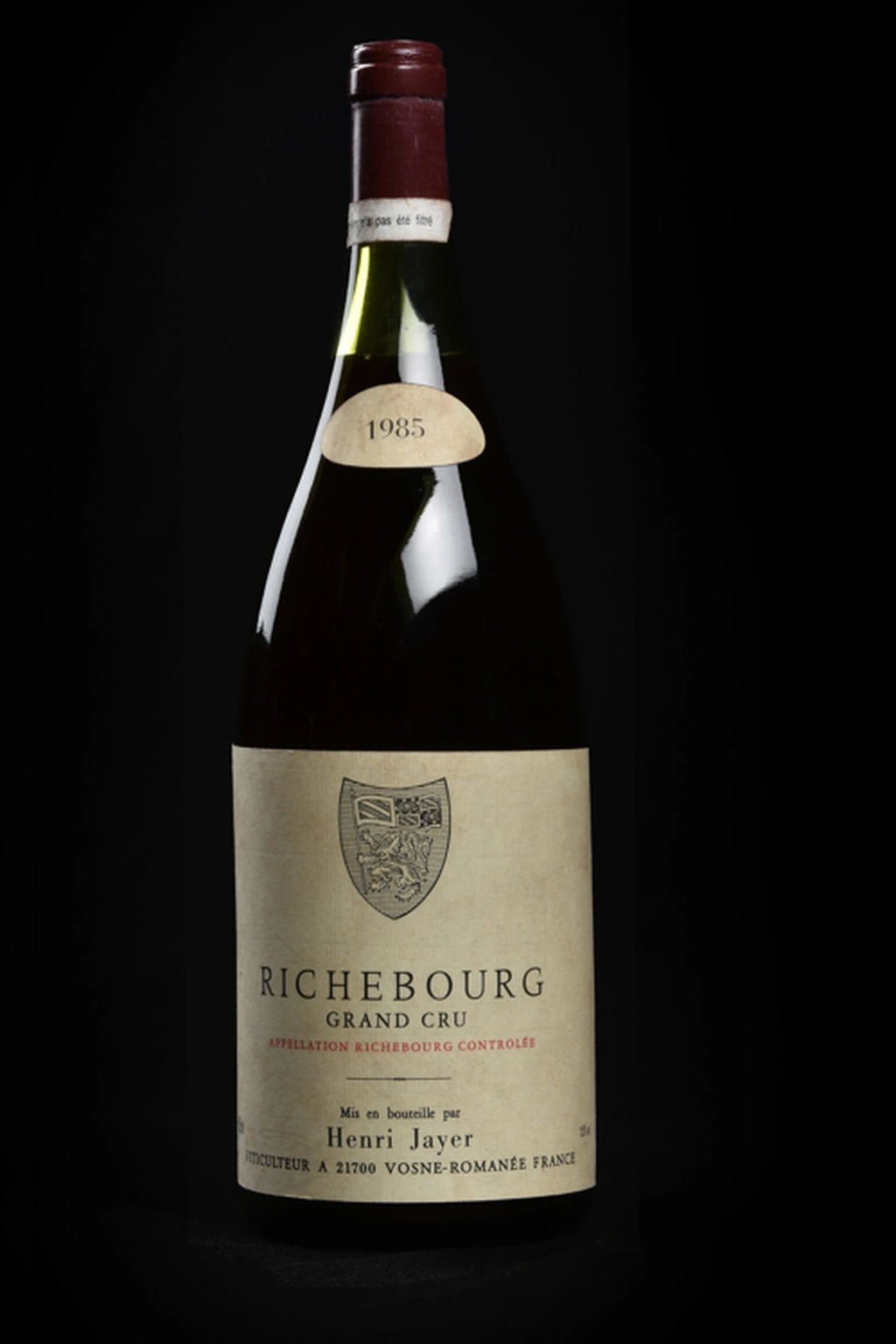 Henri Jayer: Uma garrafa de vinho tinto Richebourg Grand Cru de 1985, produzida por Henri Jayer, sobre um fundo preto.