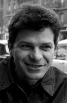 Gregory Corso: Retrato em preto e branco de um homem sorrindo em um ambiente externo.
