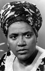 Audre Lorde: Retrato em preto e branco de uma mulher negra usando um turbante estampado e brincos pendentes.