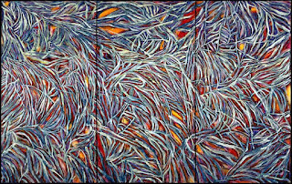 Emily Kame Kngwarreye: Uma pintura abstrata em tríptico com pinceladas densas que lembram folhagens ou galhos em tons de azul, roxo e branco sobre um fundo quente avermelhado e alaranjado.