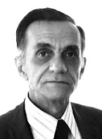 Graciliano Ramos: Retrato em preto e branco de um homem de meia-idade vestindo terno e gravata, olhando para a câmera com fundo branco.