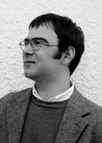 Valter Hugo Mãe: Retrato em preto e branco de um homem de óculos e suéter olhando para o lado.