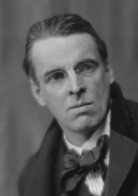 William Butler Yeats: Retrato em preto e branco de um homem com óculos e gravata borboleta, olhando ligeiramente para o lado.