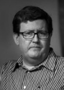 Luís Valente de Oliveira: Retrato em preto e branco de um homem usando óculos e camisa listrada.