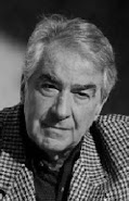 Álvaro Mutis: Retrato em preto e branco de um homem idoso com cabelos grisalhos e casaco quadriculado.