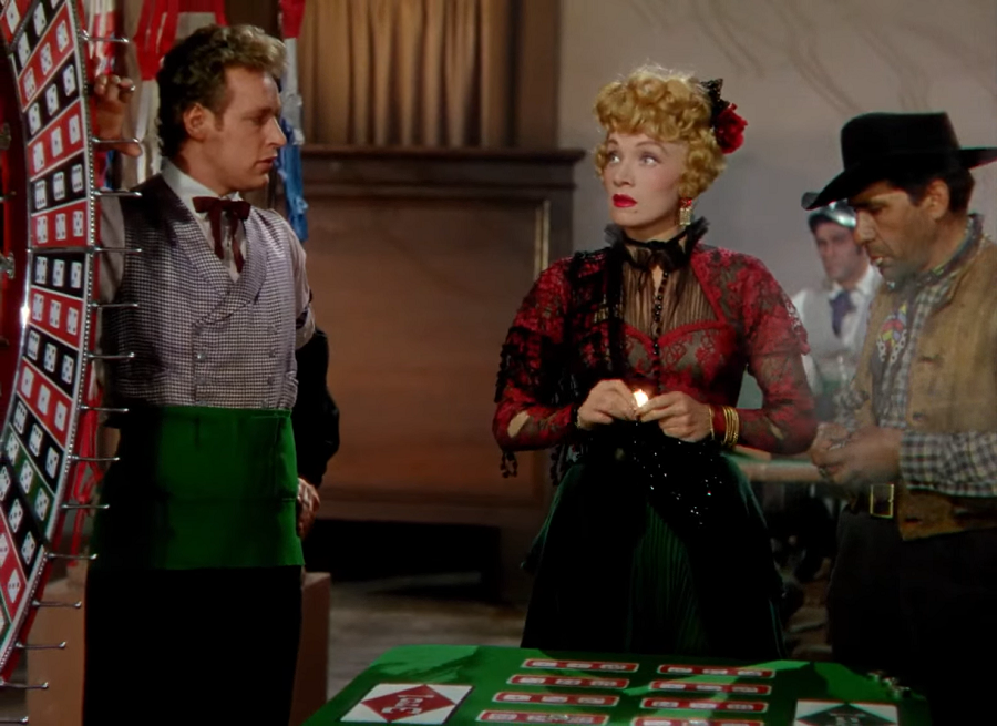 Marlene Dietrich: Uma cena de filme clássico mostrando Marlene Dietrich em um salão de jogos de estilo western, observando atentamente uma roda de apostas.