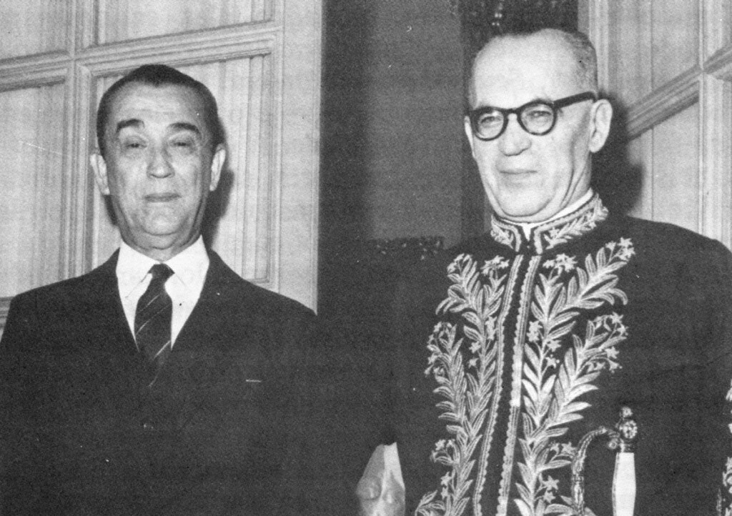 Juscelino Kubitschek e João Guimarães Rosa: Fotografia em preto e branco de Juscelino Kubitschek ao lado de João Guimarães Rosa, trajando o fardão da Academia Brasileira de Letras.