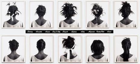 Lorna Simpson: Uma grade de fotografias em preto e branco mostrando a parte de trás da cabeça de uma mulher com diferentes penteados, acompanhadas por etiquetas de texto no centro.