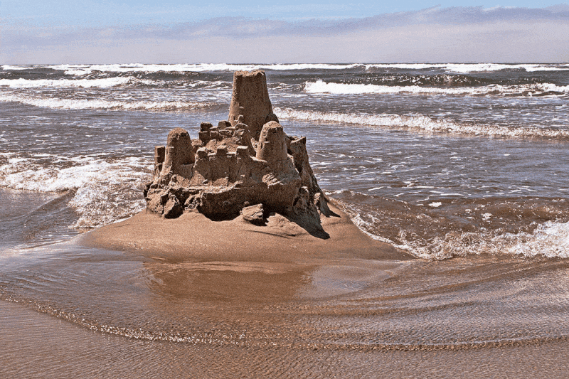 An animated gif of a sand-castle that is melting into the rising tide; through the course of the animation, the castle gradually fills up with a Matrix-style 'code waterfall' effect.