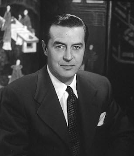 Ray Milland: Retrato em preto e branco de um homem de terno e gravata posando para a câmera.