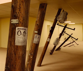 Uma imagem surrealista de postes de utilidade pública inclinados dentro de um corredor vazio com estética 'Backrooms', contendo cartazes de pessoas desaparecidas.