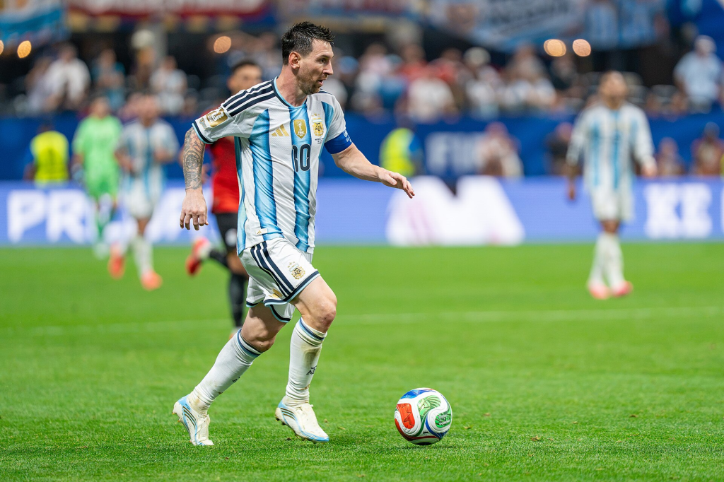 Lionel Messi: Lionel Messi conduzindo a bola durante uma partida de futebol pela seleção da Argentina.