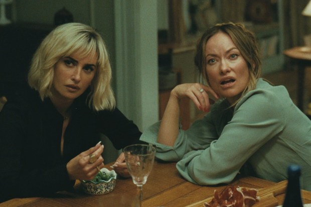 Penélope Cruz, Olivia Wilde: Uma cena de filme mostrando duas mulheres sentadas a uma mesa de jantar, uma com expressão de surpresa ou questionamento.