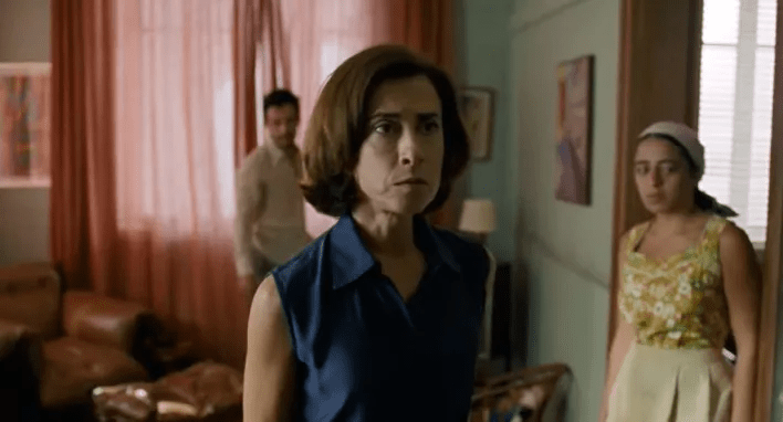 Fernanda Torres: Uma mulher com expressão séria ou preocupada em primeiro plano, em uma cena de interior que parece ser de um filme ou produção audiovisual.