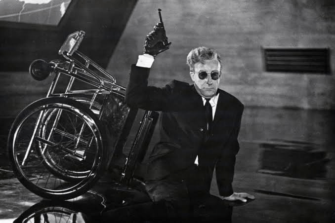 Peter Sellers: Peter Sellers como Dr. Strangelove no filme 'Dr. Strangelove or: How I Learned to Stop Worrying and Love the Bomb', levantando o braço com luva preta ao lado de sua cadeira de rodas.