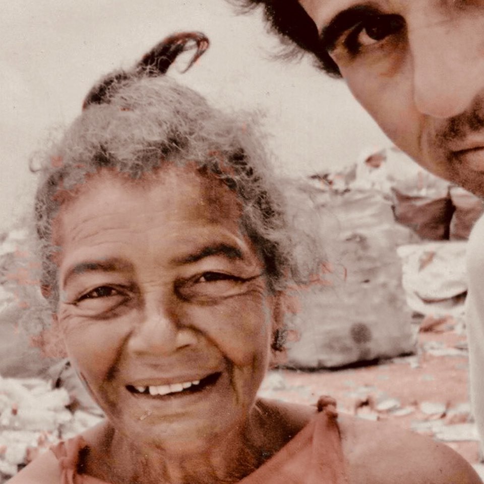 unknown: Retrato aproximado de uma senhora idosa sorrindo, com parte do rosto de um homem visível no canto superior direito.